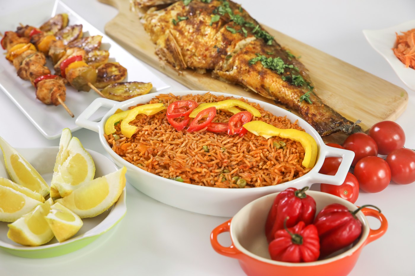 Party jollof rice with grilled fish, chicken skewers and fresh peppers